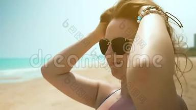 海滩上的年轻女孩调整她的头发。 近距离射击。 慢动作